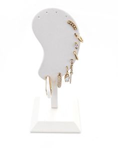 a white display stand with gold jewelry on it's face and earring holder