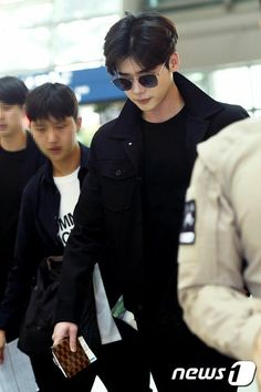 the young man is walking through an airport with his hand in his pocket and other people behind him