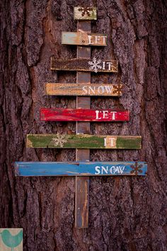 a wooden sign on the side of a tree that says let it snow, let it snow