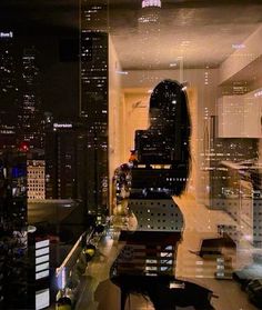 a woman standing in front of a window with cityscape behind her at night