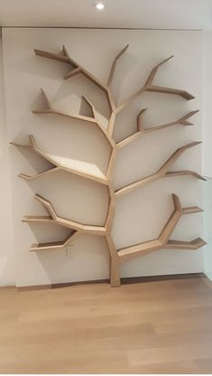 a wooden tree sculpture in the corner of a room with white walls and wood flooring