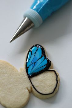 a cookie with a butterfly on it next to a pen