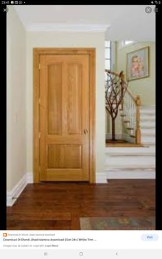 a wooden door in the middle of a room with stairs and framed pictures on the wall