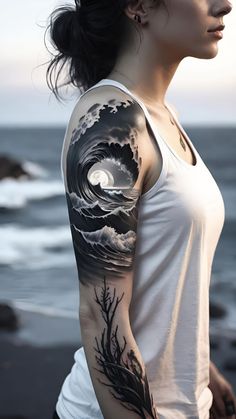 a woman with a wave tattoo on her arm and shoulder, standing next to the ocean