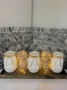 four mason jars with string lights in them