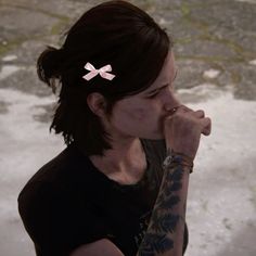 a woman with tattoos holding her hand to her face and looking at the camera while wearing a black shirt