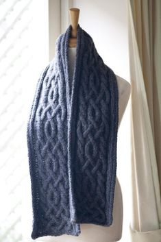 a blue knitted scarf hanging on a mannequin