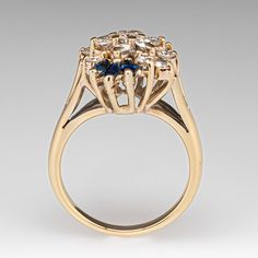 The sophisticated cluster ring is accented with fifteen (15) prong set, round brilliant cut diamonds and six (6) prong set, marquise cut natural sapphires. The ring measures 18.6mm at the top, rises 9.8mm above the finger, tapering to 2.1mm wide and 1.2mm thick at the base of the shank. Several of the diamonds are lightly chipped but nothing that can be seen without magnification. It is currently a size 6. 14k Gold Cluster Diamond Ring With Prong Setting, Cubic Zirconia Marquise-cut Multi-stone Diamond Ring, Marquise Cut Multi-stone Cubic Zirconia Diamond Ring, Multi-stone Cubic Zirconia Marquise Cut Ring, Marquise Cut Multi-stone Diamond Ring For Anniversary, Anniversary Marquise Cut Cluster Ring With Halo Setting, Marquise Cut Multi-stone Yellow Gold Diamond Ring, Anniversary Marquise Cut Halo Cluster Ring, Marquise Multi-stone Cluster Ring For Formal Occasions