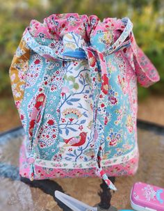 a small drawstring bag sitting on top of a table next to some scissors