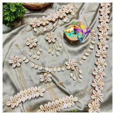 a table topped with lots of white flowers on top of a gray cloth covered in beads and chains