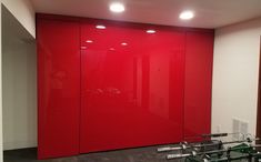 an office with red walls and black flooring in front of two large mirrors on the wall