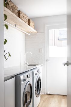 a washer and dryer in a white laundry room with open shelving on the wall