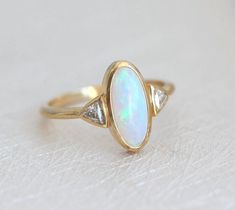 Best seller at Capucinne - Gorgeous one of a kind Australian oval opal & diamond ring perfect as a wedding or engagement ring. Available in 18k yellow gold as seen online. If you would like to have other gemstones instead of diamonds/opals Luxury Classic Opal Ring With Center Stone, Oval Cabochon Diamond Opal Ring, Heirloom Oval Opal Ring With Multi-stone, Heirloom Opal Ring With Diamond In Oval Shape, Heirloom Diamond Opal Ring Oval Shaped, Elegant Ethiopian Opal Ring For Anniversary, Elegant Opal Ring With Rose Cut Diamonds, Heirloom Oval Opal Ring For Anniversary, Art Deco Oval Cabochon Wedding Rings