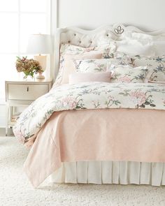 a bed with pink and white comforters in a bedroom next to a window,