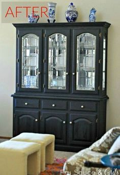 a black china cabinet with blue and white vases on top