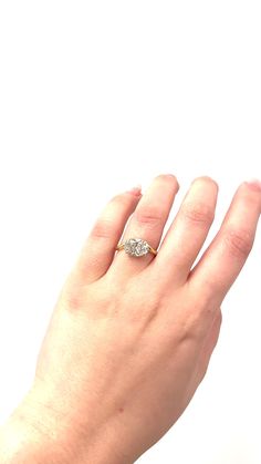 a woman's hand with a diamond ring on top of her left hand, against a white background