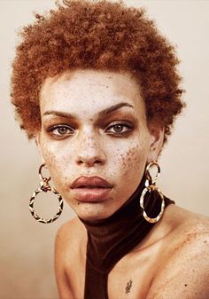 a woman with freckles on her face is wearing large hoop earrings and black choker