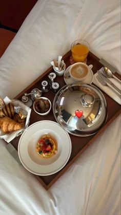 a tray with food and drinks sitting on top of a bed