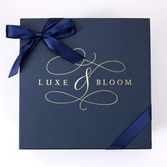 a blue and gold wedding guest book with a bow on the front that says, luxury & bloom