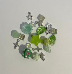 a bunch of different colored glass beads on a white surface with one green bead in the middle