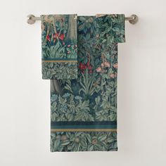 two towels hanging on a towel rack in front of a wall with flowers and leaves