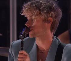 a man with curly hair is holding a microphone in his hand and looking to the side