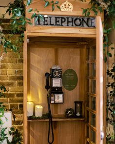 an old fashioned telephone booth with candles and pictures on the wall