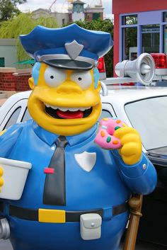 the simpsons character is holding a donut and standing next to a police car in front of a building