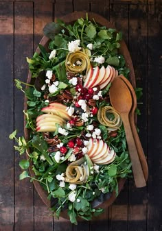 a platter with apples, cheese and greens