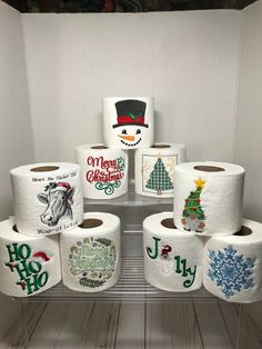 several rolls of toilet paper with christmas designs on them sitting on a shelf in a bathroom