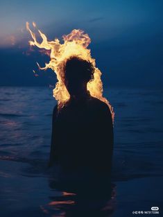 a person standing in the water with fire coming out of their head and body,