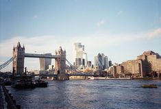 there is a boat going down the river in front of some tall buildings and a bridge