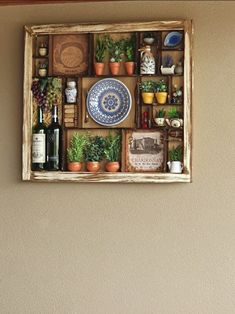 a wooden box filled with lots of plants next to a wall mounted wine bottle opener