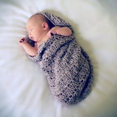 a baby wrapped in a blanket sleeping on top of a bed