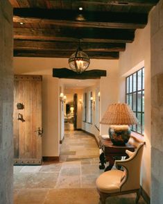 an entry way with a lamp, chair and table in the hallway between two buildings