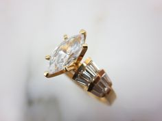 "A vintage 14k gold and CZ engagement ring, with accent stones set in the wide shoulders of the ring. Marked \"14k MUS CZ\" and acid tested, also marked with something else I cannot make out. A US size 9. Actual packaging will vary depending on item/s purchased and tape pattern available. Props/boxes shown in photos are for display purposes only, not included in this listing. As always, satisfaction is guaranteed. Thanks for shopping Vintage In Bloom More rings: http://www.etsy.com/shop/VintageI Gold Marquise Wedding Ring With Accent Stones, Gold Marquise Crystal Ring For Anniversary, Marquise Gold Topaz Ring For Wedding, Gold Marquise Cut Rings With Accent Stones, Gold Baguette-cut Topaz Ring For Wedding, Gold Baguette Cut Topaz Wedding Ring, Gold Baguette Cut Topaz Ring For Wedding, Anniversary Diamond Ring With Marquise Cut And Accent Stones, Gold Marquise Topaz Ring For Anniversary