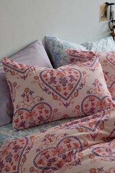 a bed covered in pink and blue sheets with pillows on top of it next to a wall