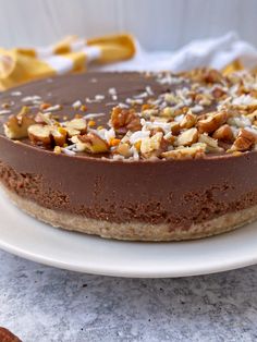 a chocolate cake with nuts on top sitting on a white plate