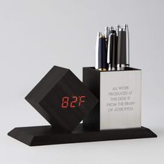 an alarm clock and pen holder with pens in it