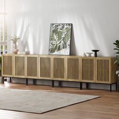 a living room scene with focus on the sideboard and plant in the foreground