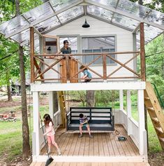 two children playing in the back yard of a small house with a porch and deck