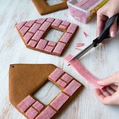 someone is cutting out some pink and brown sugar cookies with sharp scissors on a table