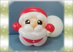 a santa clause balloon sitting on top of a blue surface with snowflakes around it