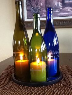 three wine bottles with candles in them sitting on a table