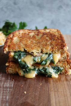 a grilled cheese and spinach sandwich on a cutting board