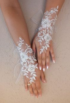 a woman's hands with white lace and flowers on them, holding onto her arm