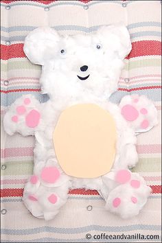 a teddy bear made out of toilet paper on top of a striped blanket with pink polka dots