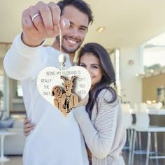 a man and woman holding up a heart shaped ornament with the words being my husband is really the only one you need