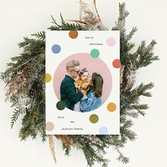 a christmas card with an image of a man and woman hugging each other on top of a wreath