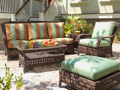 an outdoor patio with wicker furniture and green cushions